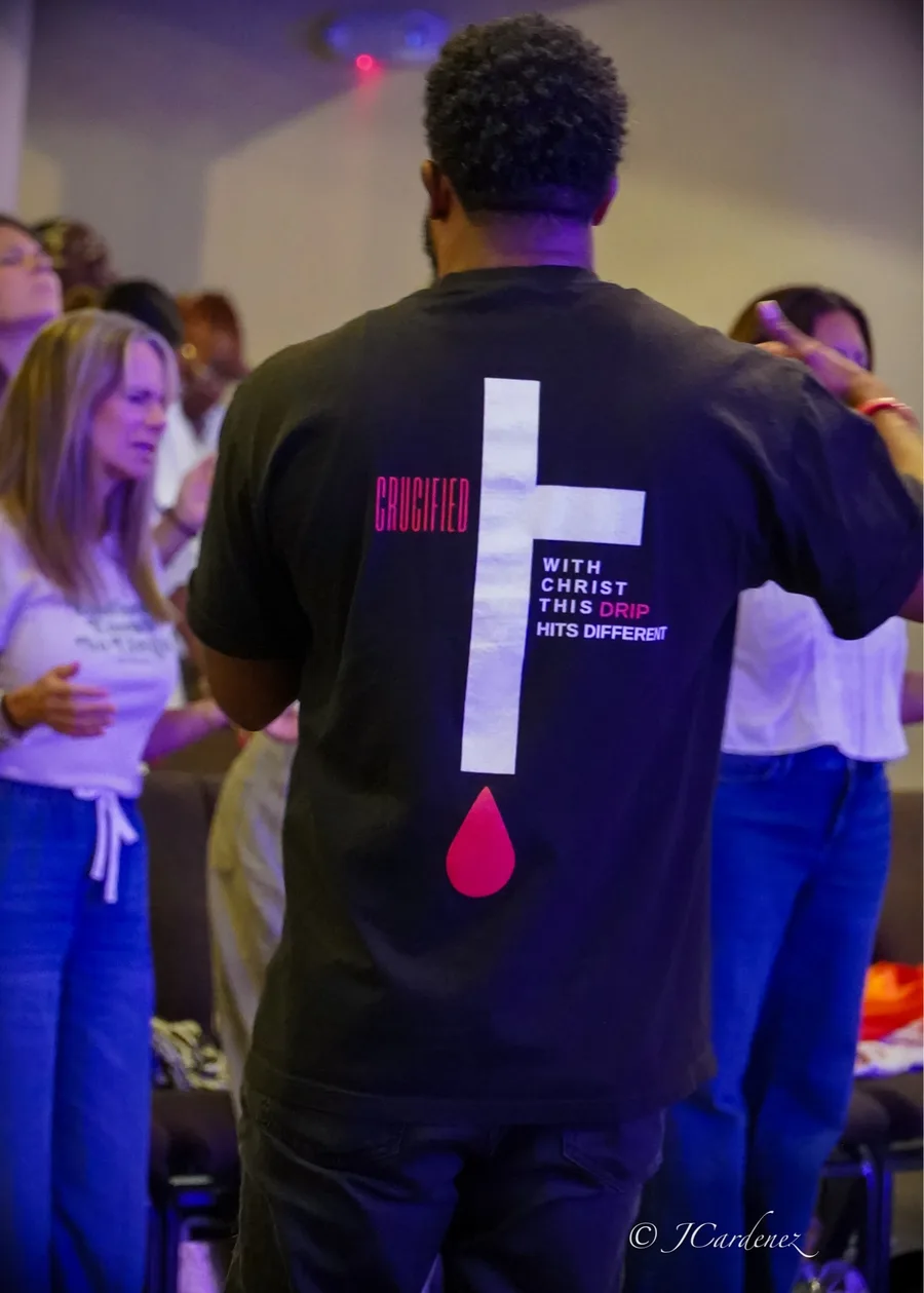 A worshiper wearing a shirt printed with a cross and the words Crucified with Christ