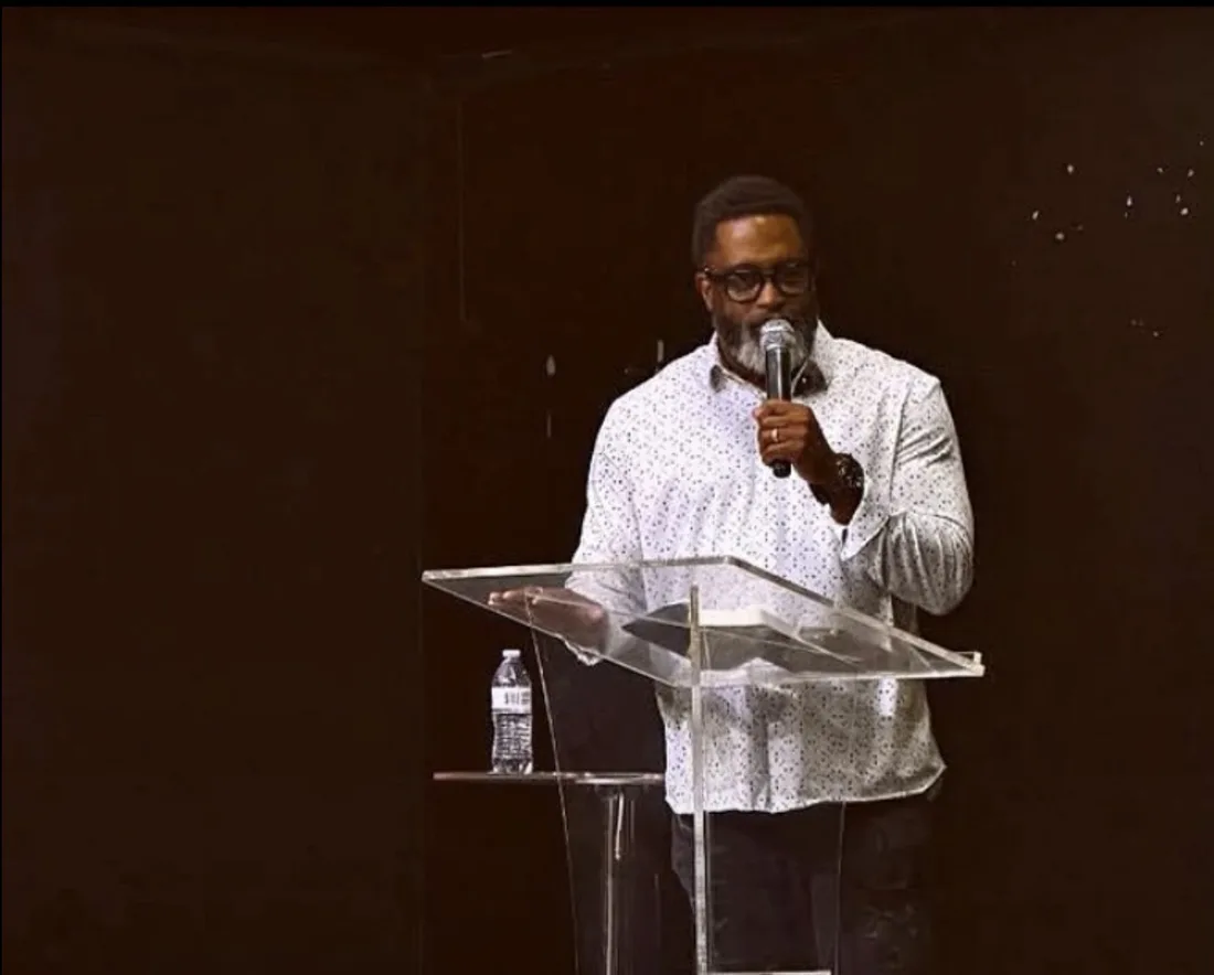 A speaker at a clear pulpit under warm stage light