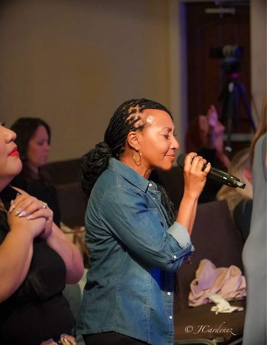 Jeanette Henderson leading worship with a microphone among the congregation